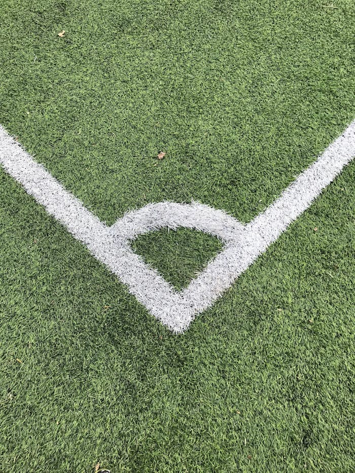 Detailed close-up of a white corner line on a green soccer field turf.